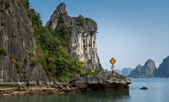Auf einer kleinen Insel in der Halong-Bucht steht an exponierter Stelle ein orangefarbenes Seezeichen; es ist auf einem kleinen Turm befestigt