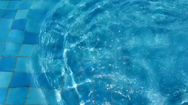 AI Generated: Top down view of crystal clear swimming pool water rippling over blue mosaic tiles
