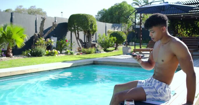 African American man sitting shirtless on deck tapping phone after ping sending reply, copy space