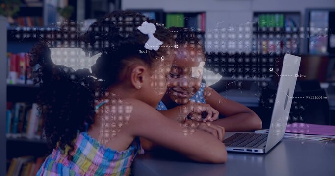 Leaning two girls in summer clothes pointing at silver laptop on library table, with purple binder