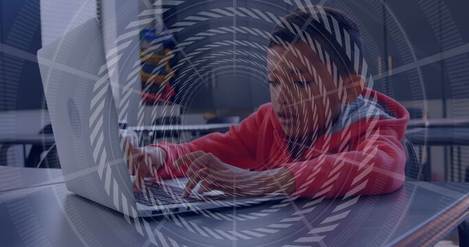 Typing boy wearing red hoodie knit beanie leaning over laptop at cafeteria table backpack watermark