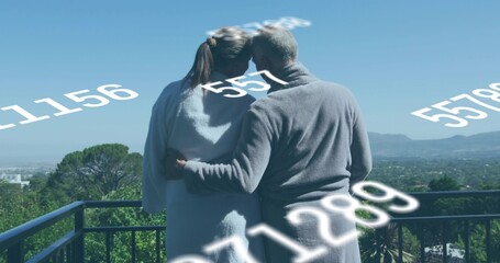 Standing senior couple in robes on terrace by metal railing, viewing data overlay © vectorfusionart