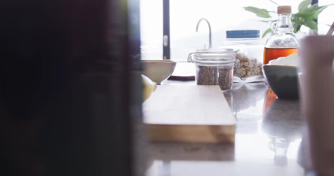 Camera shifting right revealing cutting board clamp jar bowl on kitchen countertop centering