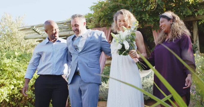 Newlyweds descending steps postvows under pink pergola, bride white holding calla man guiding groom