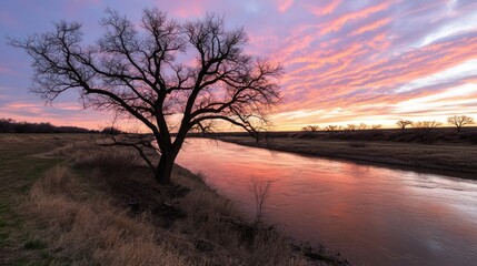 Naklejka premium Serene Sunset Reflection Over Calm River with Silhouetted Tree and Vibrant Sky