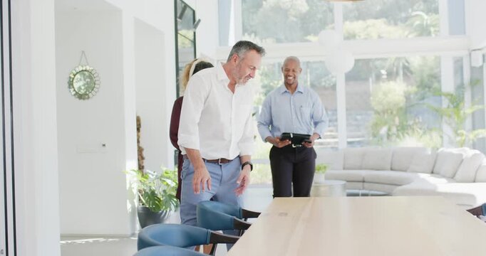 Visiting couple and host entering open room preparing seating for tour placing tablet on wood table