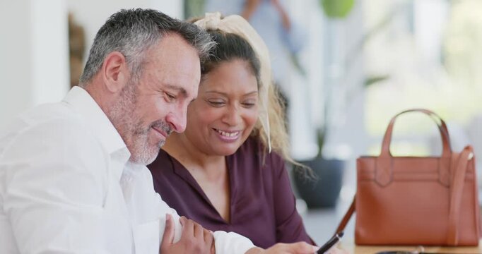 Diverse couple signing documents at office table after review, finalizing forms with pen