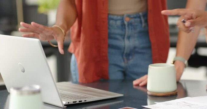 Diverse female team reaching toward laptop at office counter pointing at color swatches for review