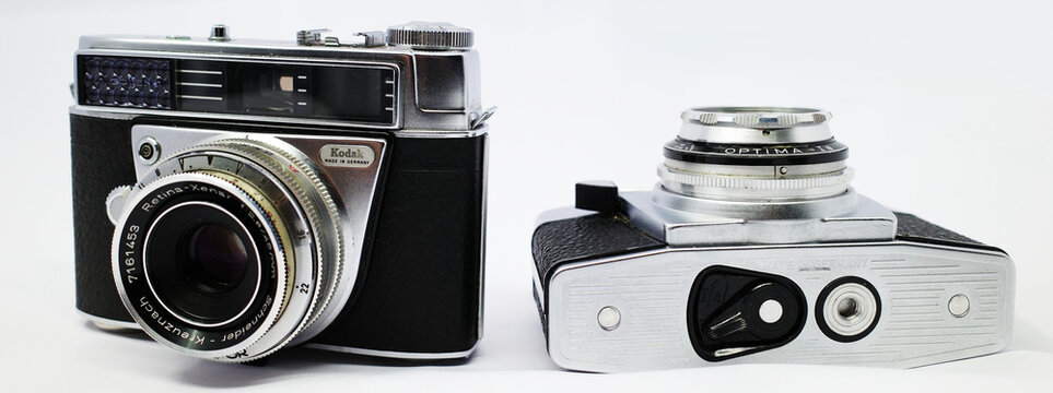 Itterbeck, Germany March 4 2026 - Two vintage cameras are depicted. On the left is a Kodak Retina Automatic II camera with a Schneider Kreuznach lens  On the right lies an Agfa Optima 1a camera 