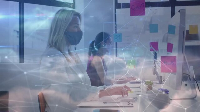 Vertical video: Overlay drifting masked woman white top working and typing in office with notes