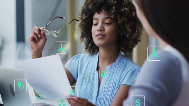 Reading woman in blue blouse adjusting glasses at desk, with document, laptop and floating icons
