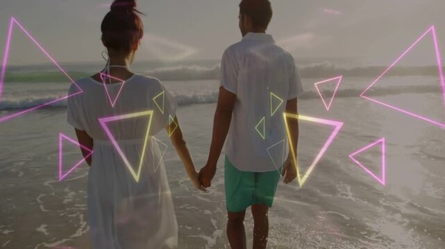 Couple walking ocean shore, stepping into water and causing neon triangles to cover them for travel
