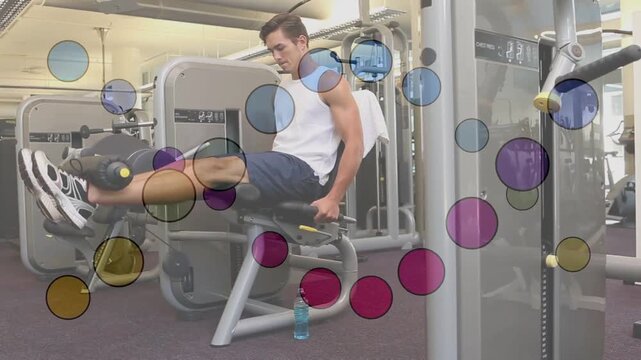 Vertical video: Positioning feet behind roller, man in tank top training leg extensions on machine