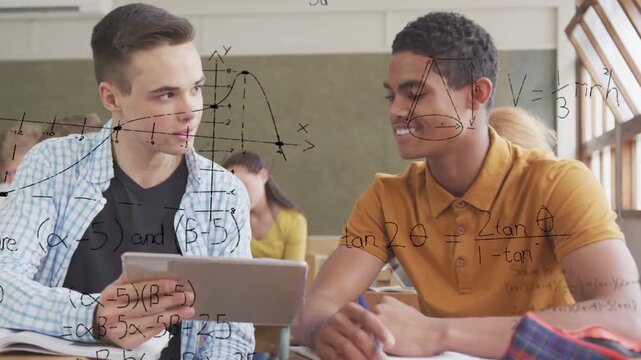 Diverse teenage male students sitting at classroom desk, studying math on tablet and open textbook