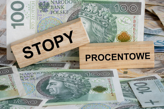 The words &lsquo;Stopy Procentowe&rsquo; written in Polish on wooden blocks, English: &lsquo;Interest Rates&rsquo;, lying on Polish banknotes.
