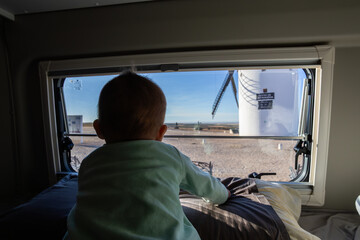 Obraz premium Baby looking out camper van window seeing windmill
