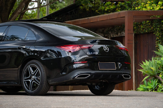 Black Mercedes CLA 200 rear quarter side view low angle, Luxury compact sedan near green trees