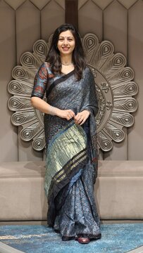 Elegant Indian woman in ajrak print saree with lagdi patta border posing indoors, showcasing traditional ethnic fashion and graceful festive style against ornate decor backdrop.