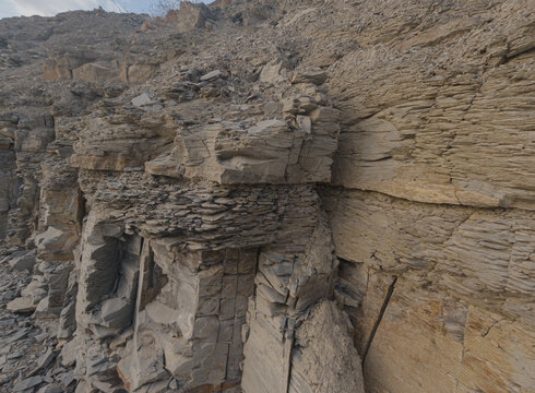 Rocky cliff face with layered sedimentary formations outdoors during day