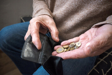 Starszy mężczyzna liczy drobne monety z portfela. © Blaszko