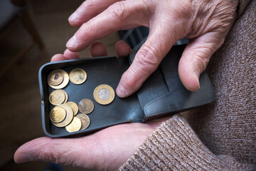 Starszy mężczyzna liczy drobne monety z portfela. © Blaszko