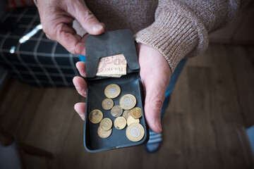 Starszy mężczyzna liczy drobne monety z portfela. © Blaszko