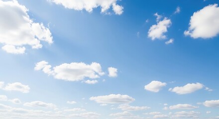 Fototapeta premium Fluffy white clouds drifting across a bright blue sky with sun glare