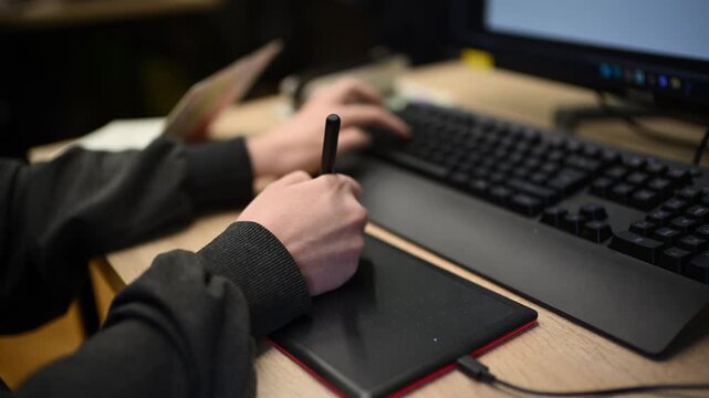 Person using graphic tablet connected to computer for digital design work