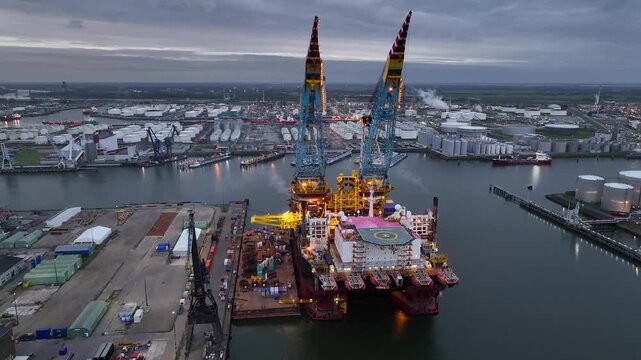 Rotterdam, Netherlands. Drone flight over industrial area with cargo ports, containers and a semi-submersible ship, heavy lifting crane. Machines designed for work at sea