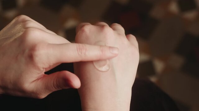 A close-up of fingers applying and spreading pain-relieving ointment onto a hand. Concept for arthritis treatment and joint care for pain.