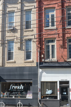 exterior building facades and signs of Fresh Kitchen & Juice Bar and Le Swan, restaurants, located at 894 and 892 Queen St W, Toronto