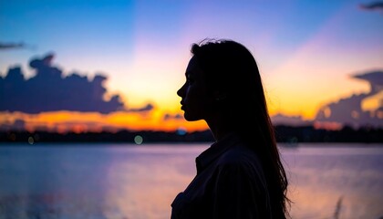 Fototapeta premium Silhouette of a Woman Contemplating the Sunsets Beauty.