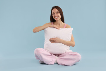Obraz premium Beautiful woman with pillow on light blue background. Space for text