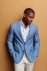 Obraz premium Confident Man in Light Blue Blazer Posing Against Tan Background in Modern Fashion