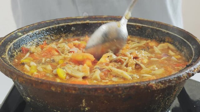 In a deep cast-iron skillet, vegetables and chicken are simmering in sauce