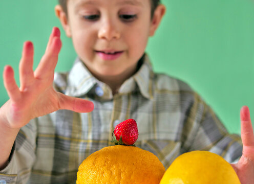 Child Balancing Strawberry on Top of Lemon, Fresh Yellow Citrus and Red Berry, Playful Healthy Eating and Fruit Selection Concept