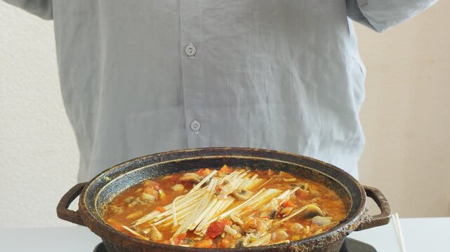 Vegetables simmer in a deep cast-iron skillet with chicken and udon, stirring