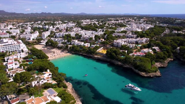4K Drone Pull Back from Cala Cala d'Or Beach. Cinematic Aerial View of Turquoise Bay, White Luxury Villas with Swimming Pools and Yacht Anchored in Sea. Mallorca Balearic Islands Spain. High Quality