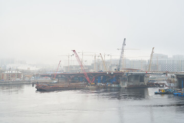 Fototapeta premium Foggy bridge construction with cranes and site engineer oversight