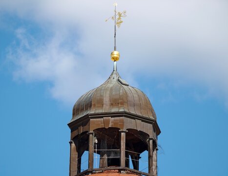 Ancient religious tower. Weathered wooden bell tower featuring ornate metal finial and cross