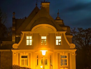 Vintage house illuminated at night. Ancient residence with radiant lamps and illuminated windows © Vladimir