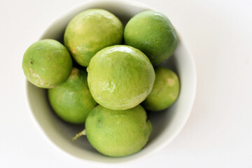 Obraz premium Top view of fresh green limes arranged on a clean white table, creating a bright and minimal citrus background. Ideal for concepts of freshness, healthy lifestyle, natural ingredients, summer drinks,
