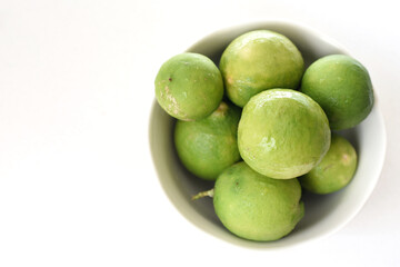 Obraz premium Top view of fresh green limes arranged on a clean white table, creating a bright and minimal citrus background. Ideal for concepts of freshness, healthy lifestyle, natural ingredients, summer drinks