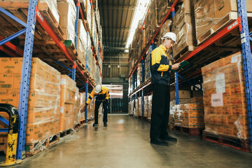 Obraz premium Two male employees work warehouse their duties including checking inventory moving goods forklift receiving shipping goods checking stock loading goods on pallets recording data into digital device.