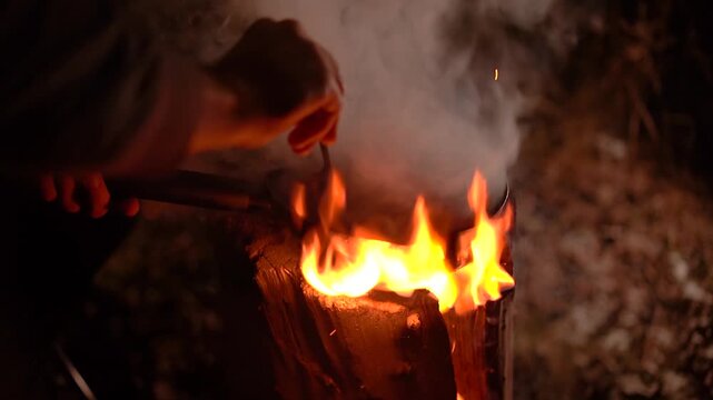 close up of sausages frying in pan on top of burning swedish torch log