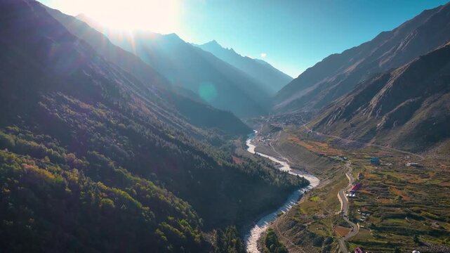 Cinematic Drone shot of the winding Baspa River bathed in golden hour sunlight in Chitkul, Kinnaur, Himachal Pradesh.