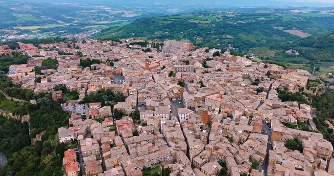 чAerial drone view Orvieto Italy perched volcanic tuff cliff. Ancient stone city historical architecture summer landscape high angle perspective beautiful scenery professional video.