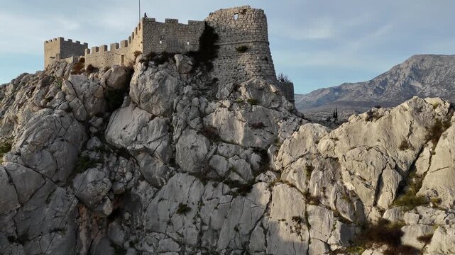 Drone panoramic shot of Omis, Croatia Castle showing full  view of the historical fortess flowing into Adriatic sea, scenic aerial landscape of Dalmatian coast with mountains and nature