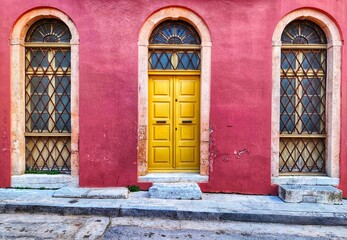 Photo of a colorful neoclassical facade with a yellow wooden door in the historic Plaka neighborhood of Athens, Greece. © Antonios