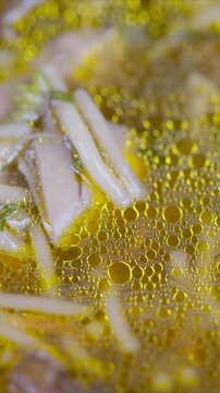Warm savory soup. Shimmering mushroom broth closeup. Fragrant broth with delicate enoki noodles rising. Comforting pot of simmering broth with herbs and mushrooms